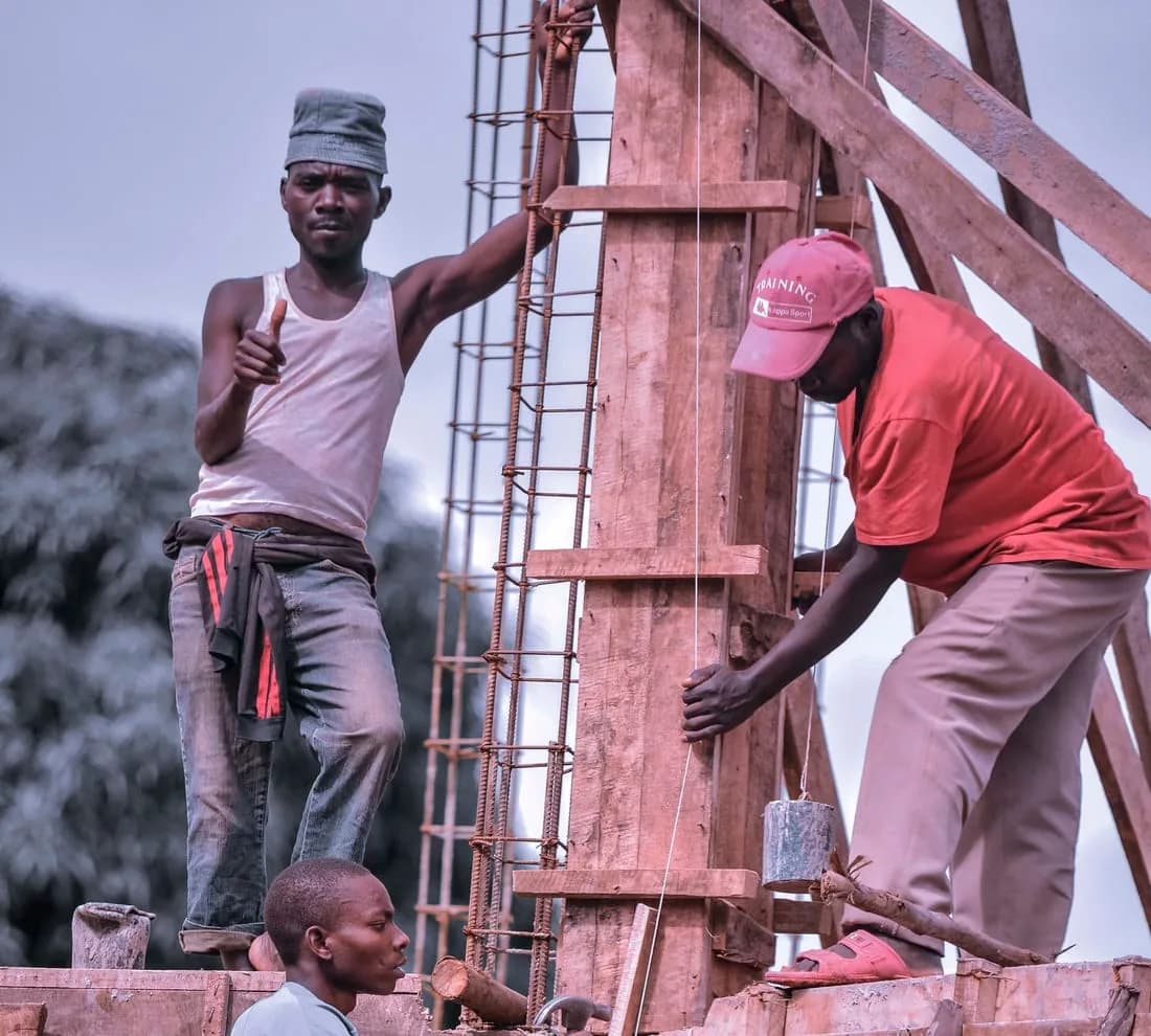 Deux ouvriers coffrant une colonne de béton